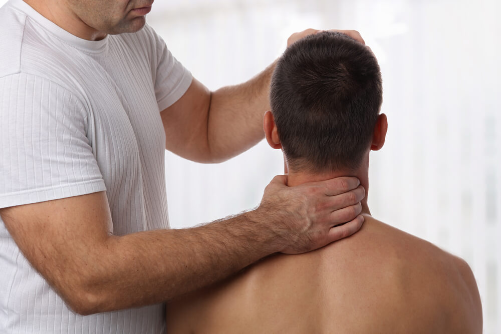 A man holding another man's neck and head as he gently adjusts his spine